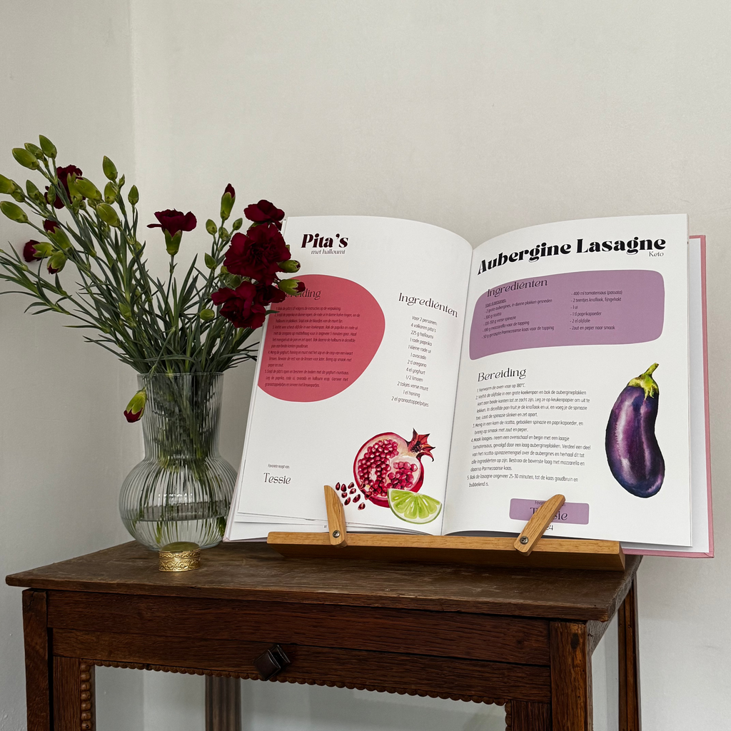 Personal cookbook open on a book stand, showing recipe pages for pitas and aubergine lasagne