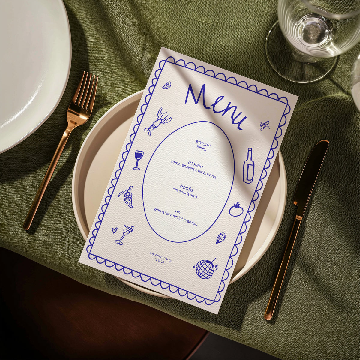 Blue hand-drawn dinner party menu card on a plate with green table linen